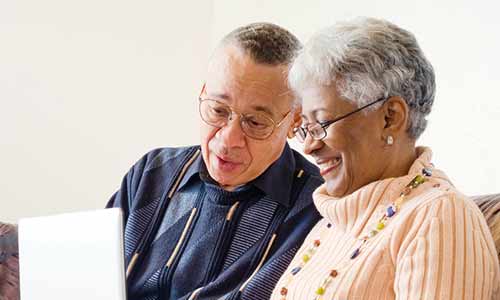 An older man and woman looking at the laptop